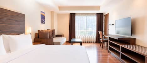 A hotel room with a large bed, a desk, a chair, a television, and a window with curtains.