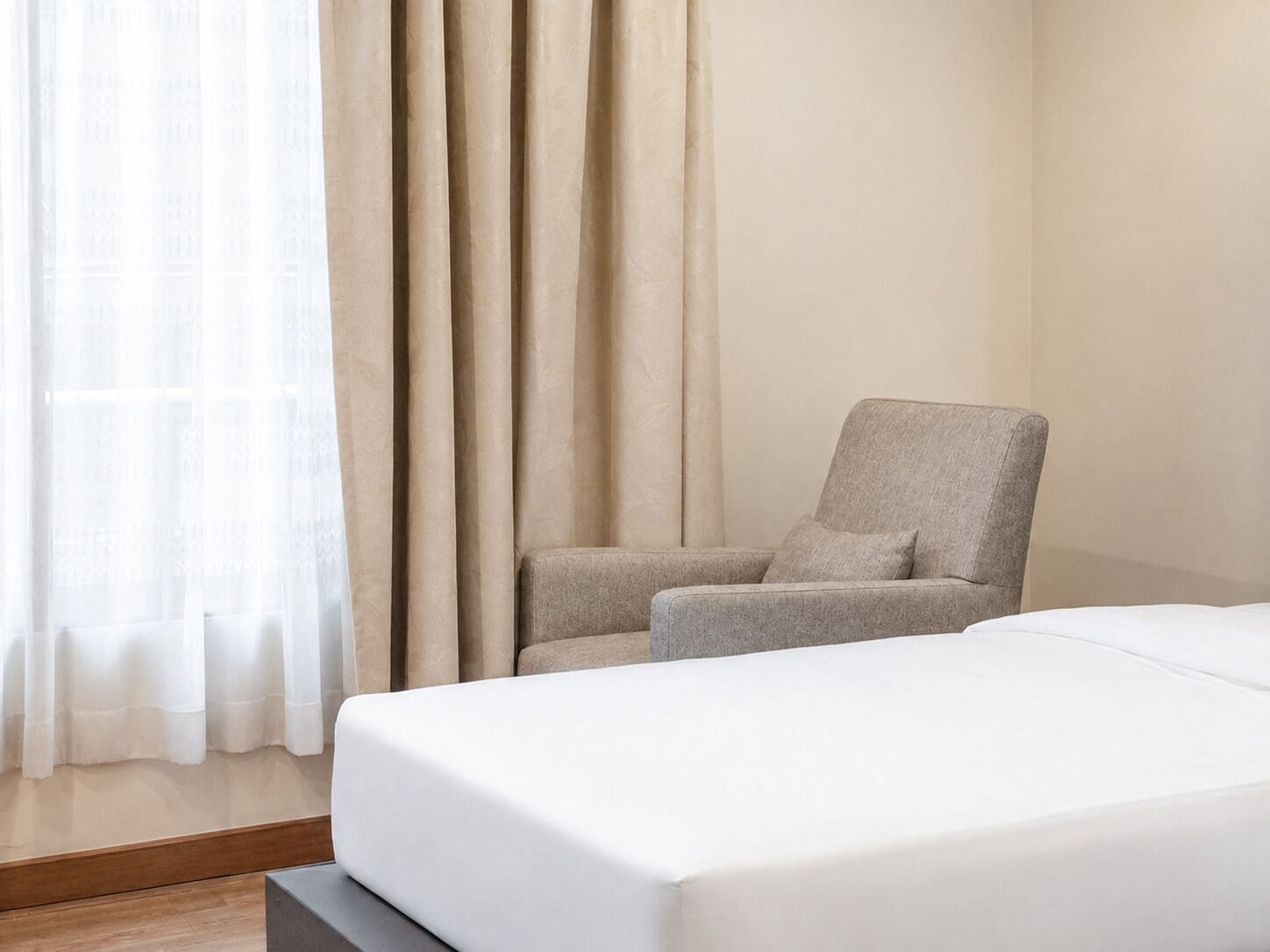 A hotel room with a bed, a chair, and curtains.
