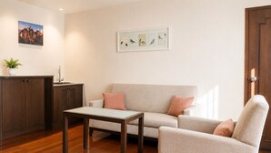 A living room with a sofa, armchair, coffee table, and a cabinet. - Journeyhub Sukhumvit 26 Bangkok (Bangkok)