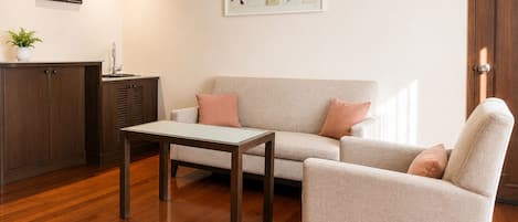 Una sala de estar con sofá, sillón, mesa de centro y aparador.