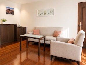 A living room with a sofa, armchair, coffee table, and a cabinet. - Journeyhub Sukhumvit 26 Bangkok (Bangkok)