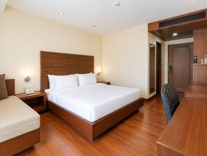 Una habitación de hotel con cama de madera, mesitas de noche, un escritorio y un armario.