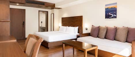 Una habitación de hotel con una cama, un sofá, una mesa de centro y un escritorio.