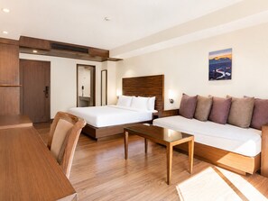 Ein Hotelzimmer mit Bett, einer Couch, einem Couchtisch und einem Schreibtisch.