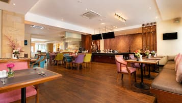 Un hall de hotel con bar, zonas de estar y una televisión.