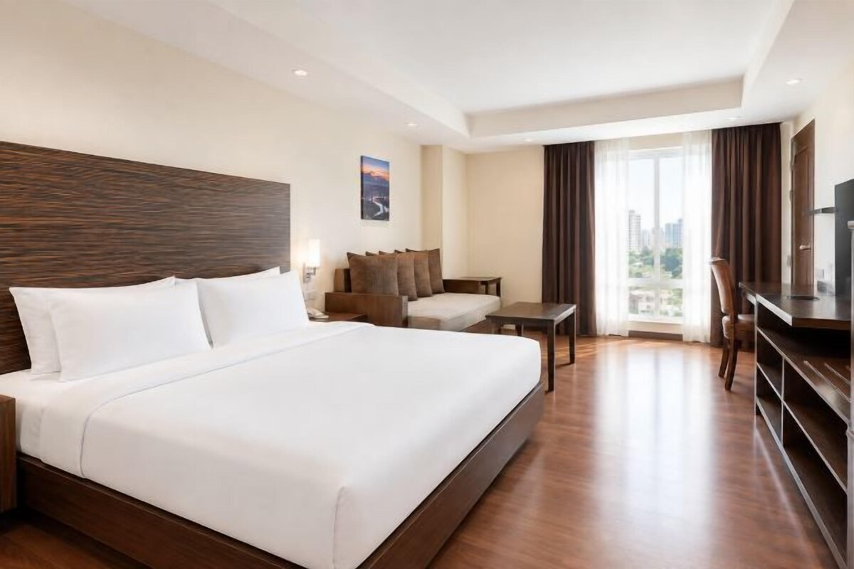 Una habitación de hotel con una cama grande, un escritorio, una silla y un televisor.