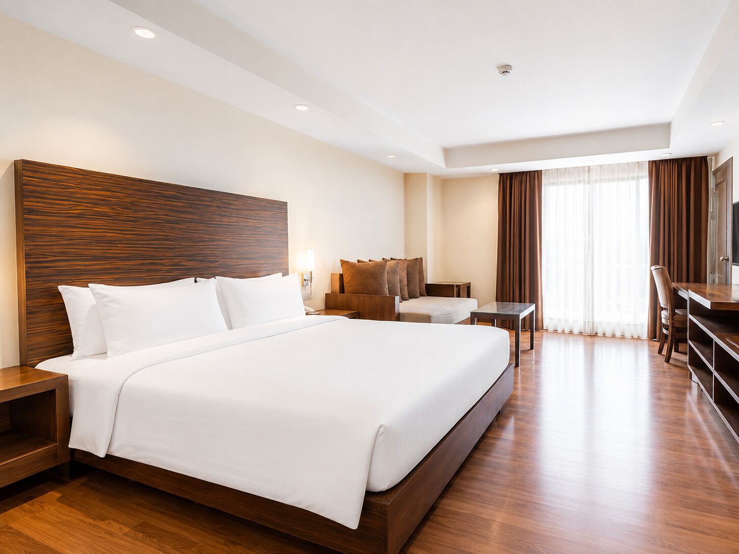 A hotel room with a large bed, a desk, a chair, and a television.
