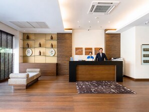 Un área de recepción con un mostrador de madera, un sofá y una alfombra estampada.