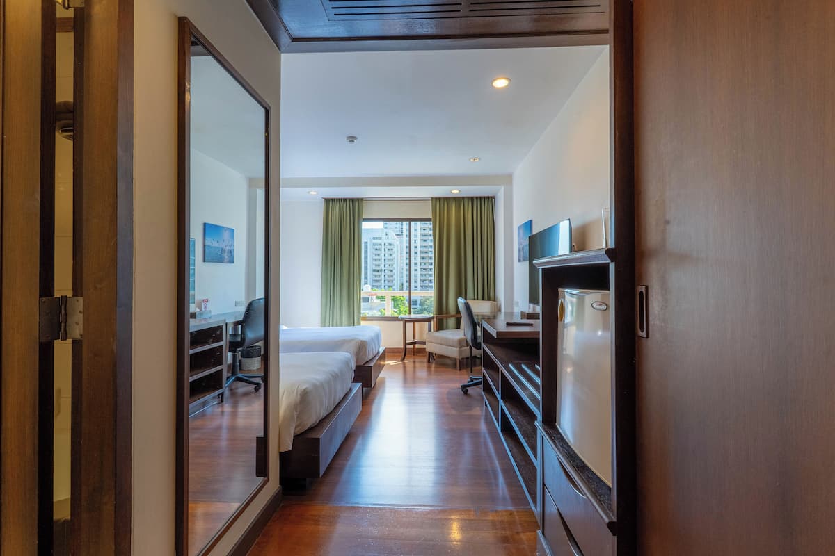 Una habitación de hotel con cama, escritorio, silla y refrigerador.