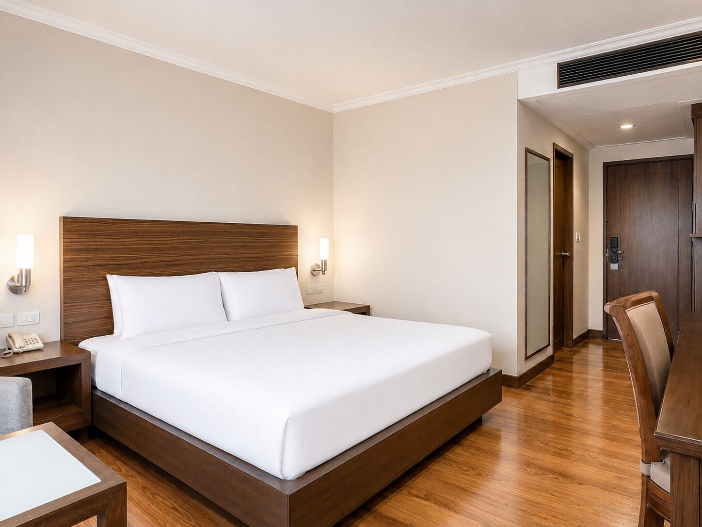 Une chambre d’hôtel avec un grand lit, des tables de chevet, un bureau et une chaise.