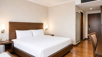 Habitación de hotel con una cama grande, mesitas de noche, un escritorio y una silla.