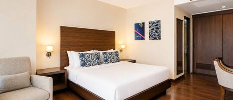 Una habitación de hotel con una cama grande, una mesita de noche, una silla y un armario.