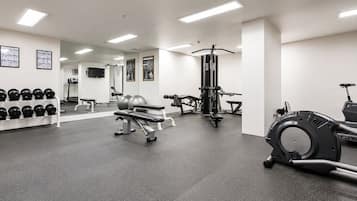 A gym with exercise equipment, a bench, and a wall-mounted dumbbell rack.
