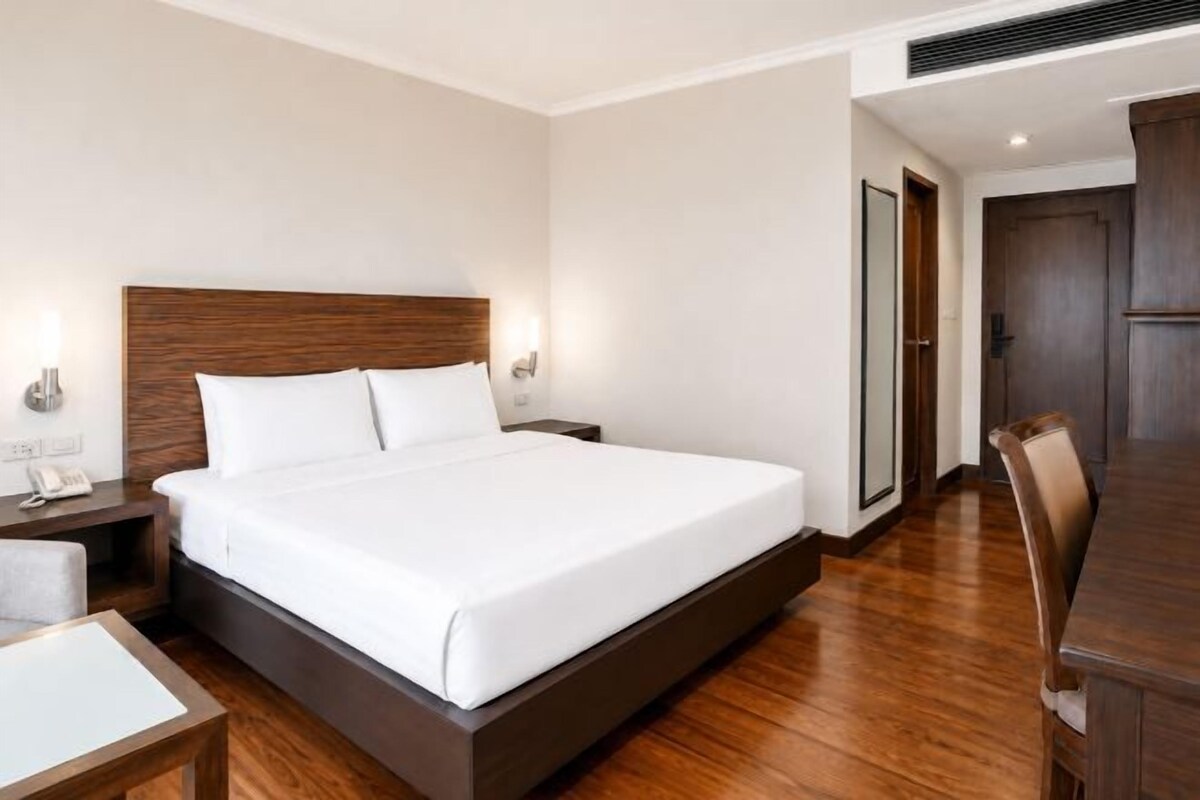 Una habitación de hotel con una cama grande, mesitas de noche, un escritorio y una silla.