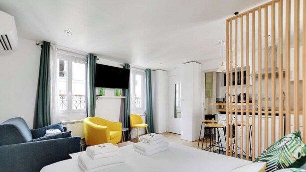 Ett modernt hotellrum med en säng, en soffa, en stol, ett skrivbord och en liten köksdel.