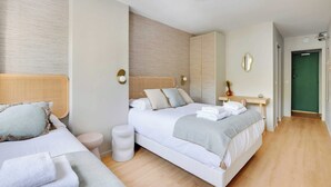 Une chambre d’hôtel moderne avec deux lits, un petit bureau et une porte verte.