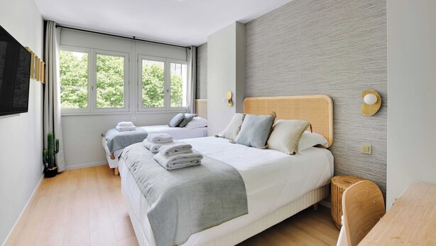 Une chambre d’hôtel moderne avec un grand lit, un lit plus petit et un coin salon.