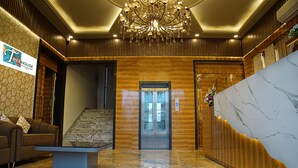 A hotel lobby with a marble reception desk, a staircase, and a chandelier. - TreeHouse The Royal Chandra Mahal (Jaipur)