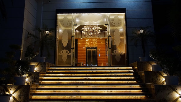 A well-lit entrance with a wooden door, steps leading up to it, and decorative wall panels. - TreeHouse The Royal Chandra Mahal (Jaipur)