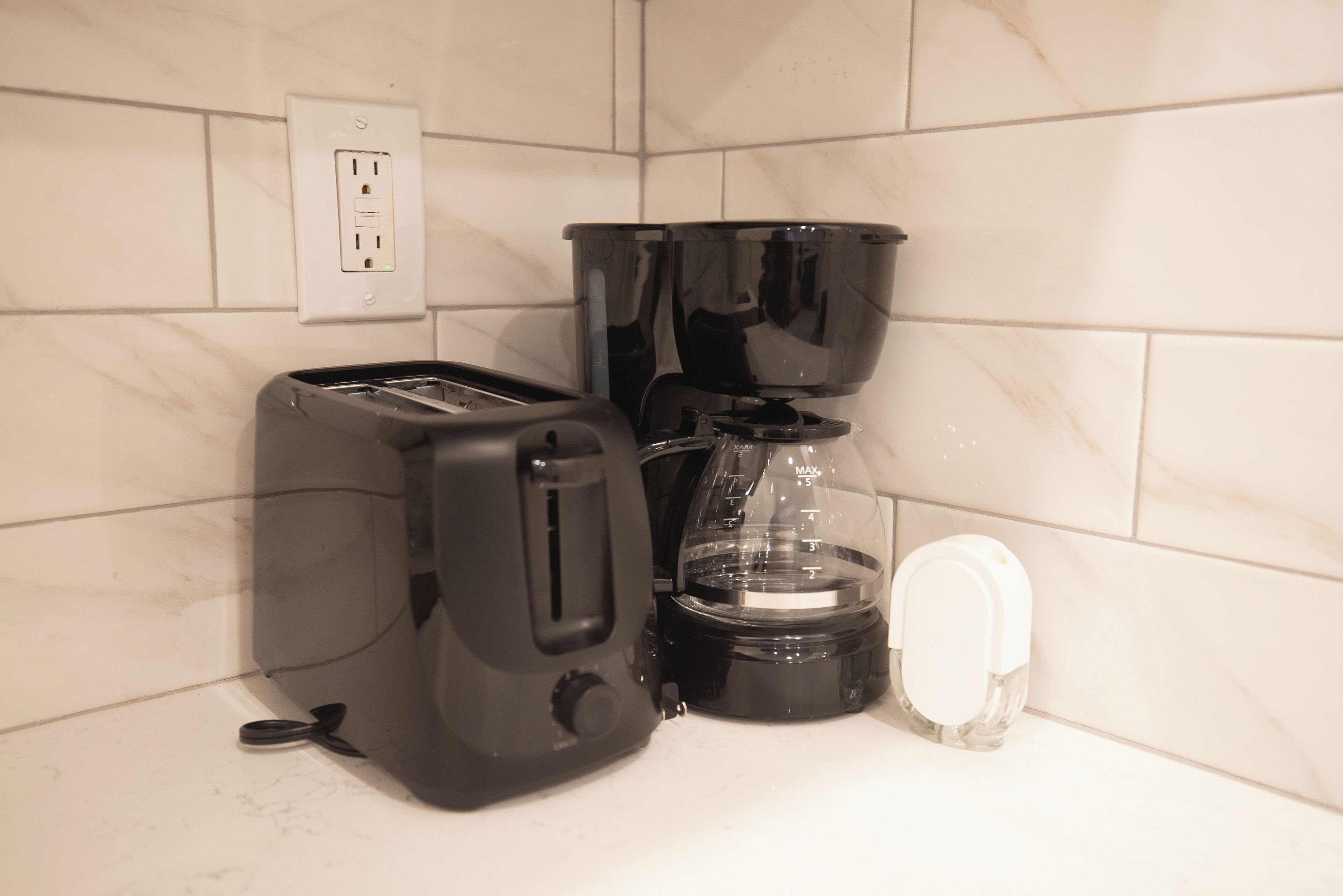Ett kök med en brödrost, en kaffebryggare och en vattenautomat.
