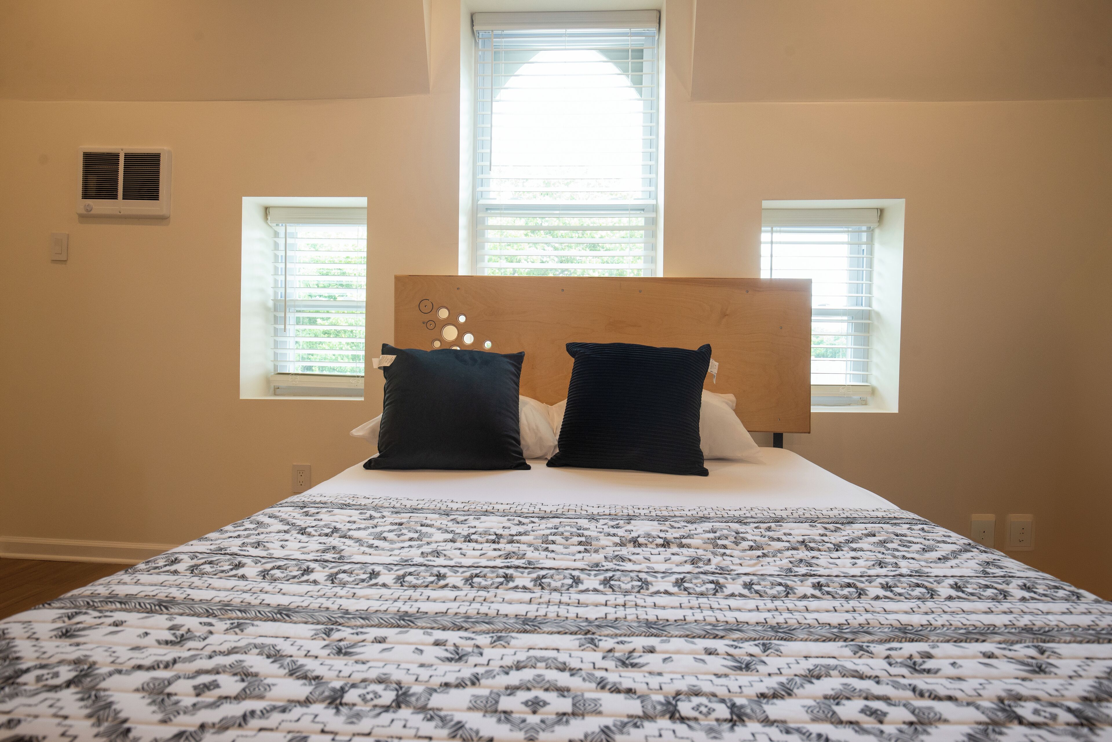A bedroom with a bed, two windows, and a headboard.