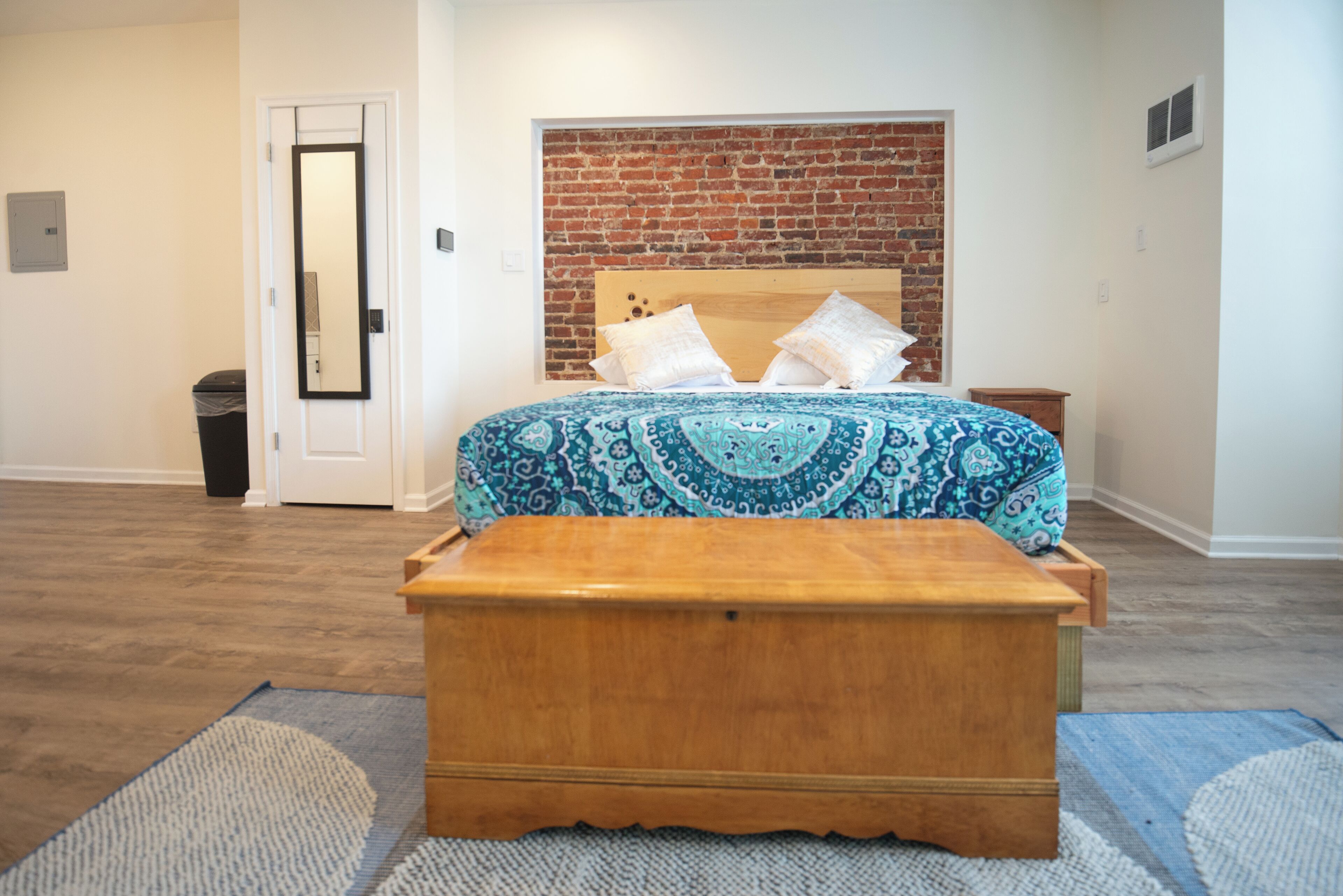 A bedroom with a wooden bed, a brick wall, and a white door.