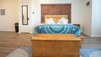 A bedroom with a wooden bed, a brick wall, and a white door.