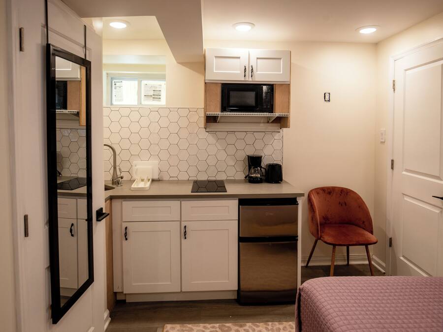 A compact kitchen with white cabinets, a microwave, a coffee maker, and a dishwasher.