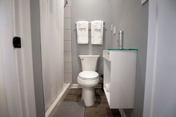 A small, modern bathroom with a toilet, a sink, and two towels hanging on the wall. - Diamond Suites Philadelphia Center (Philadelphia)