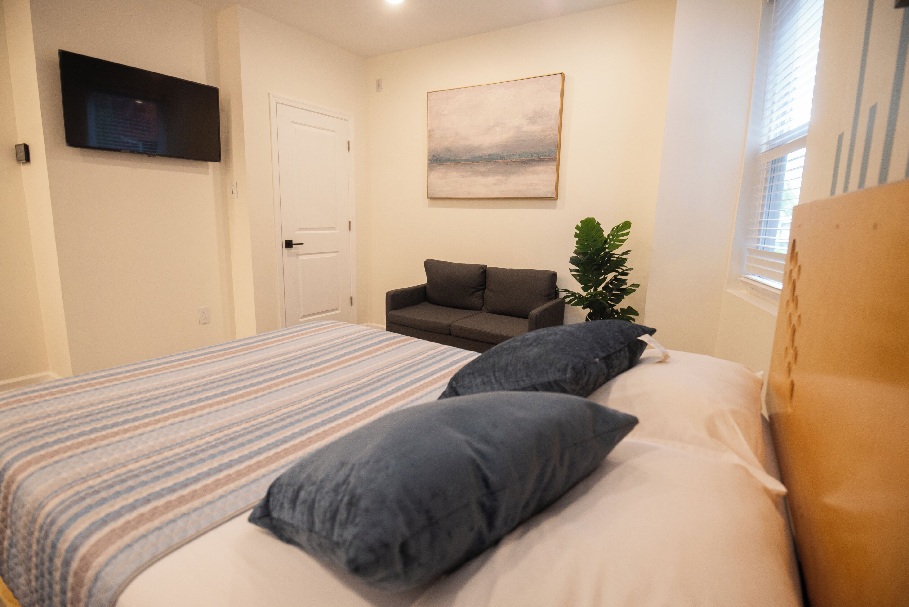A bedroom with a bed, a sofa, a TV, and a painting on the wall.