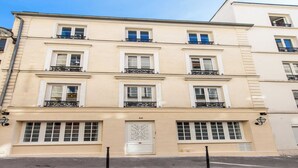 A multi-story building with a symmetrical facade, featuring evenly spaced windows and balconies with wrought iron railings. - Charming private room in Pigalle (Paris)