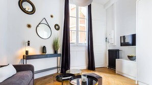 A modern living room with a sofa, two round tables, a fireplace, and a television. - Elegant studio - 2P - TrocadÃ©ro / Eiffel Tower (Paris)