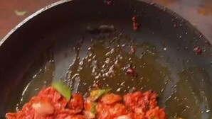 A pan with a red sauce and green leaves, possibly a cooking dish. - oshiana farm (Pehowa)