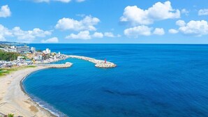 Une zone côtière avec une plage, une jetée et des bâtiments en arrière-plan.