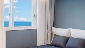 Une chambre à coucher avec un lit, une fenêtre avec des rideaux et une vue sur la mer.