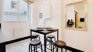 A dining area with a table set for four, a large mirror, and a radiator on the wall.