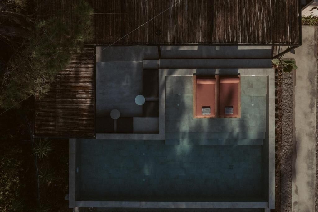 A modern house with a flat roof, a small patio area, and a large open space.