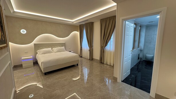 A modern bedroom with a large bed, a nightstand, and a bathroom visible through an open door. - Hypnos - Luxury Suite in Pescara (Pescara)