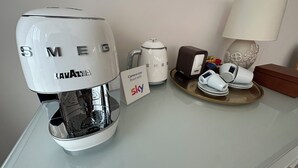 Una macchina da caffè, un bollitore, un cartello con scritto Sky Room con Vista, una lampada e un vassoio con tazze e una scatola su un tavolo.