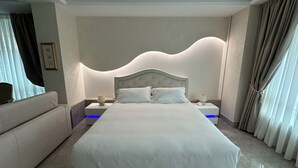 A modern hotel room with a large bed, a nightstand, a lamp, and a sofa. - Hypnos - Luxury Suite in Pescara (Pescara)