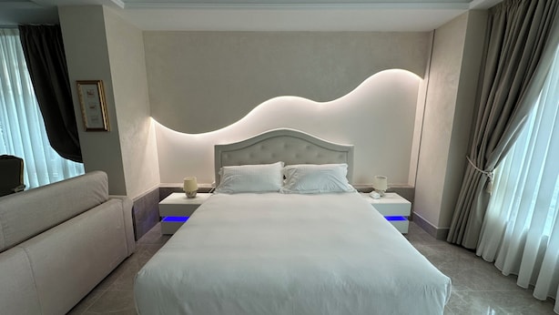 Una moderna camera d'albergo con un letto grande, un comodino, una lampada e un divano.
