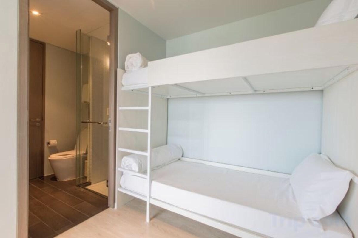 A bunk bed with a shelf above, a toilet, and a shower area.