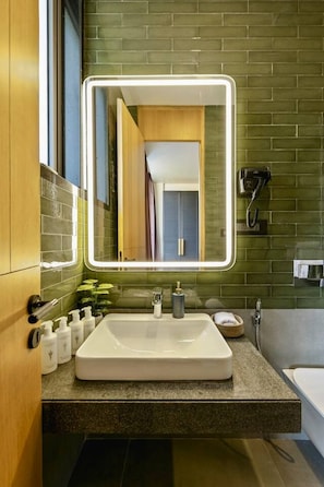 A modern bathroom with a large mirror, a white sink, and a hairdryer on the wall.