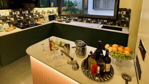 Una cocina moderna con una isla central, armarios oscuros y un ventanal con vistas a una zona residencial.