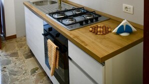 A compact kitchen with a gas stove, a sink, and white cabinets.