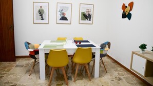 A dining area with a white table, yellow chairs, and framed artwork on the wall.