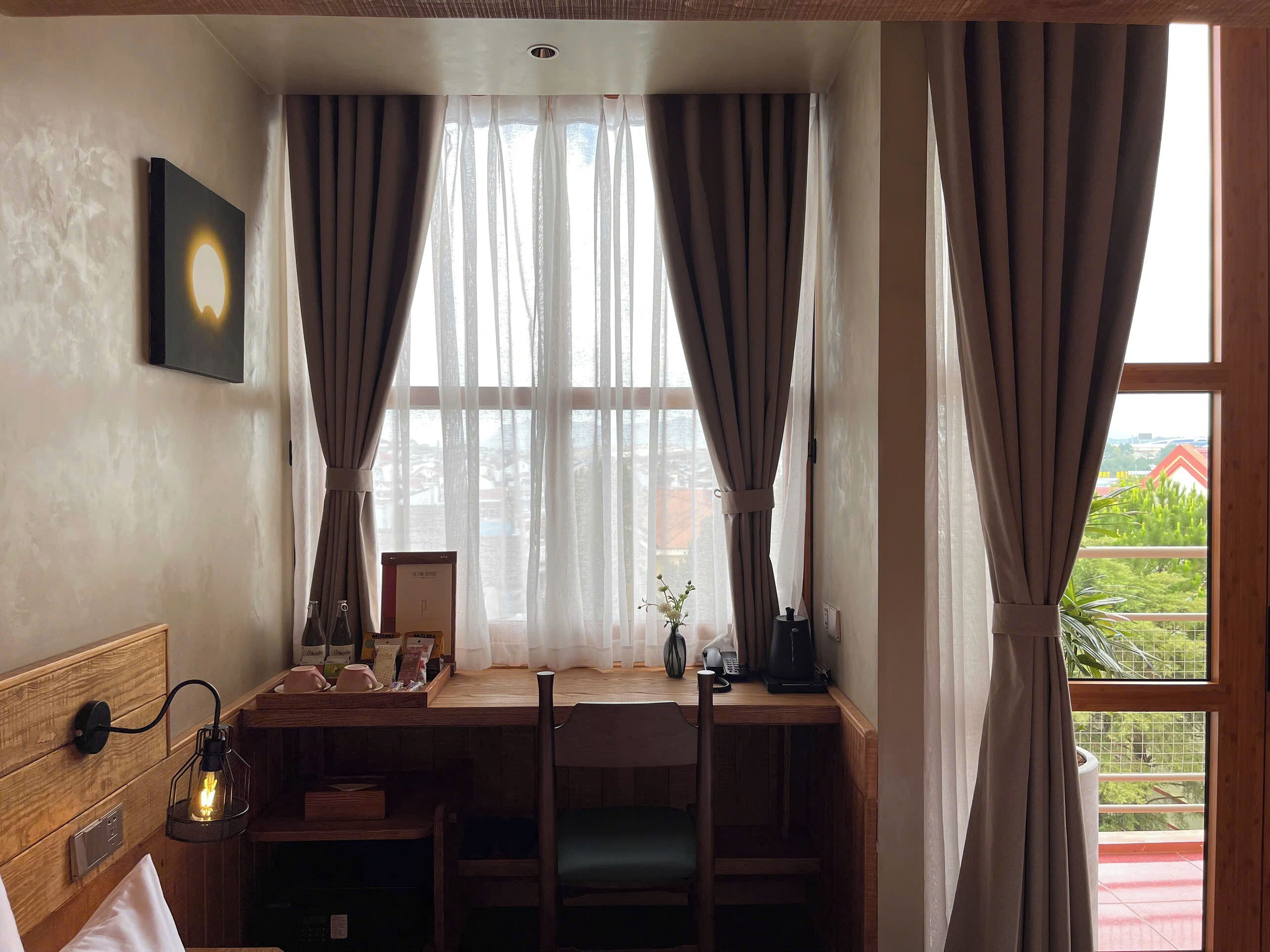 A cozy room with a wooden desk, a bed, and a window with curtains.