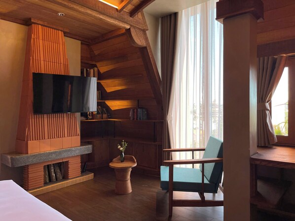 Una habitación acogedora con televisión, chimenea, estantería y ventana con cortinas.