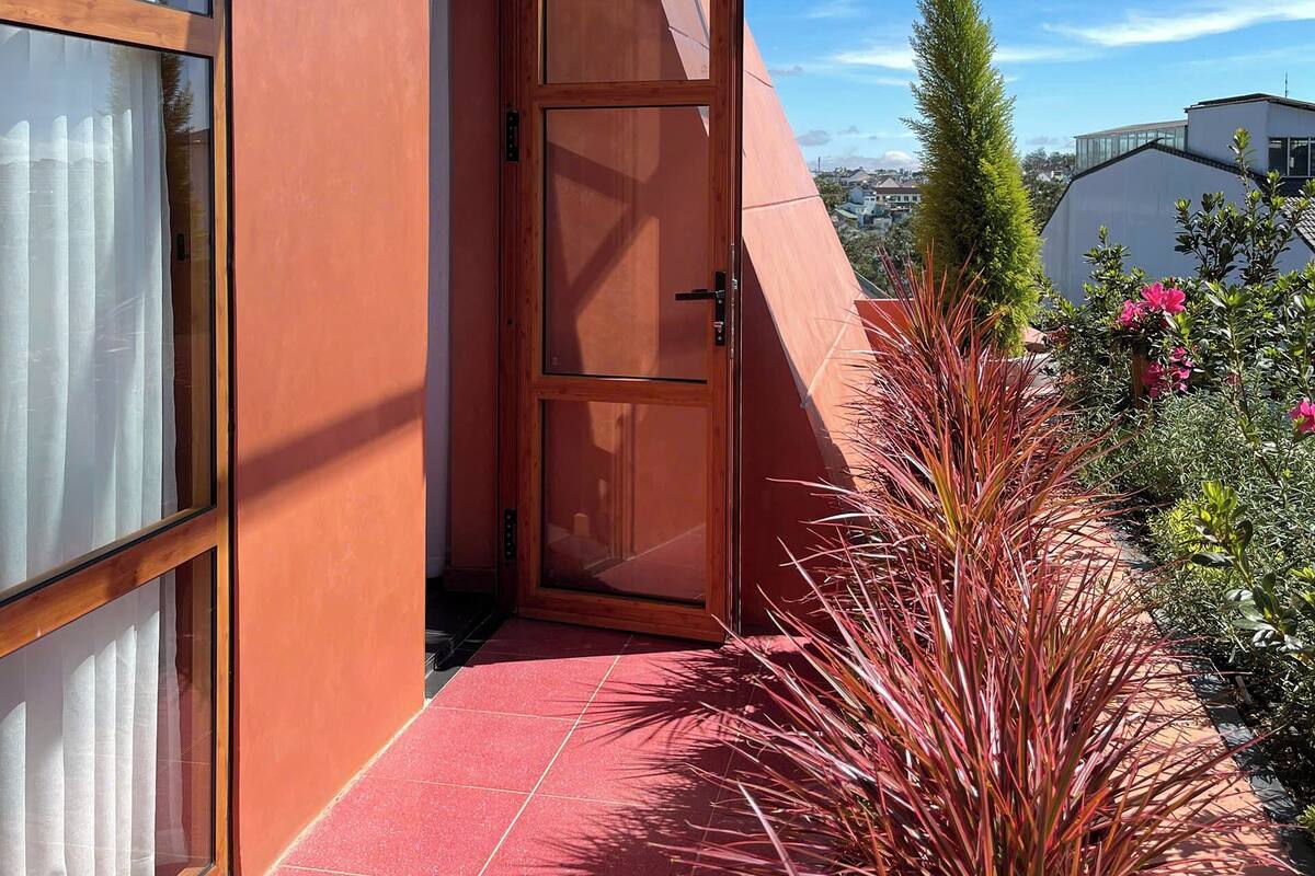 Un bâtiment moderne avec une porte en verre, une allée piétonne aux carreaux rouges et un ciel dégagé.
