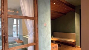 A modern interior with a wooden ceiling, a seating area with a bench and a small table, and a glass door with a curtain. - The Pink Boutique Hotel (Cam Ly - Da Lat)
